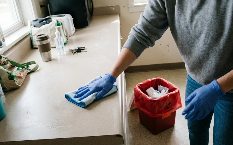 Gloved technician applying hospital-grade disinfectant during biohazard remediation